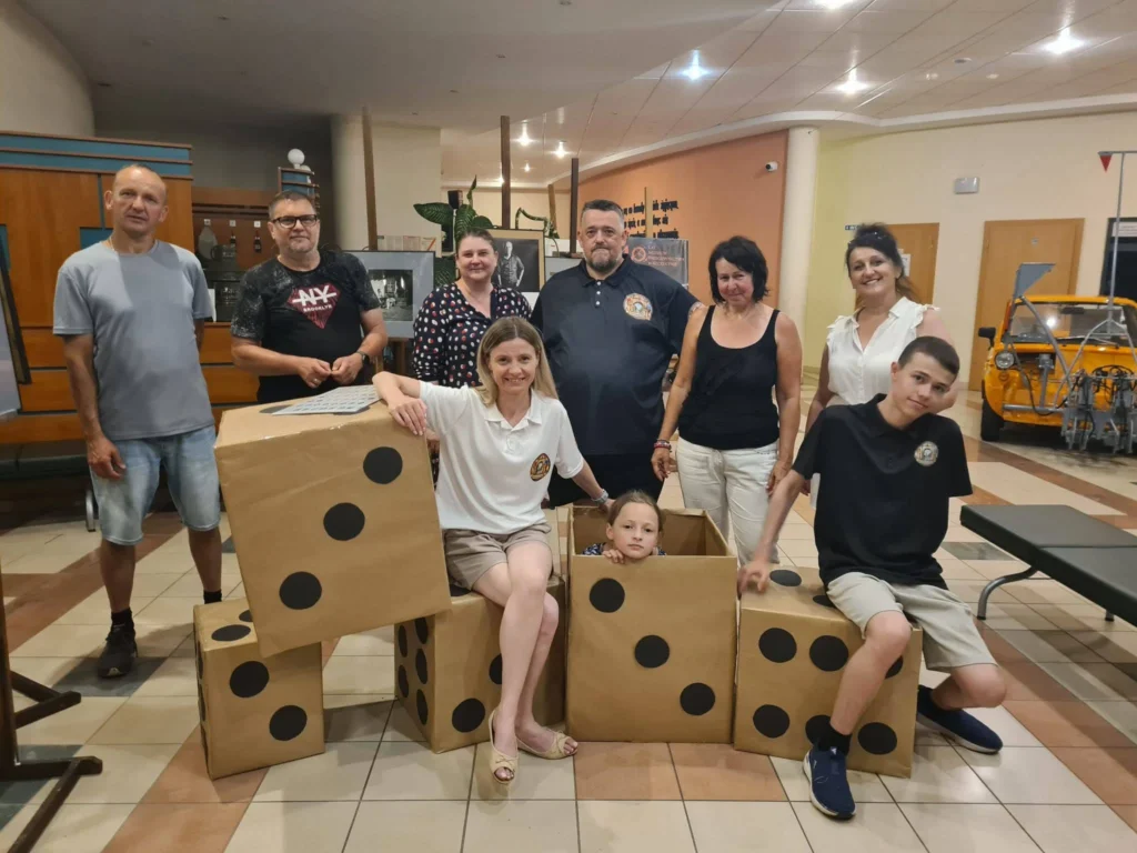 Uczestnicy spotkania Dąbrowskiego Klubu Gier Planszowych pozują z dużymi kostkami do gry podczas wydarzenia w Dąbrowie Tarnowskiej.